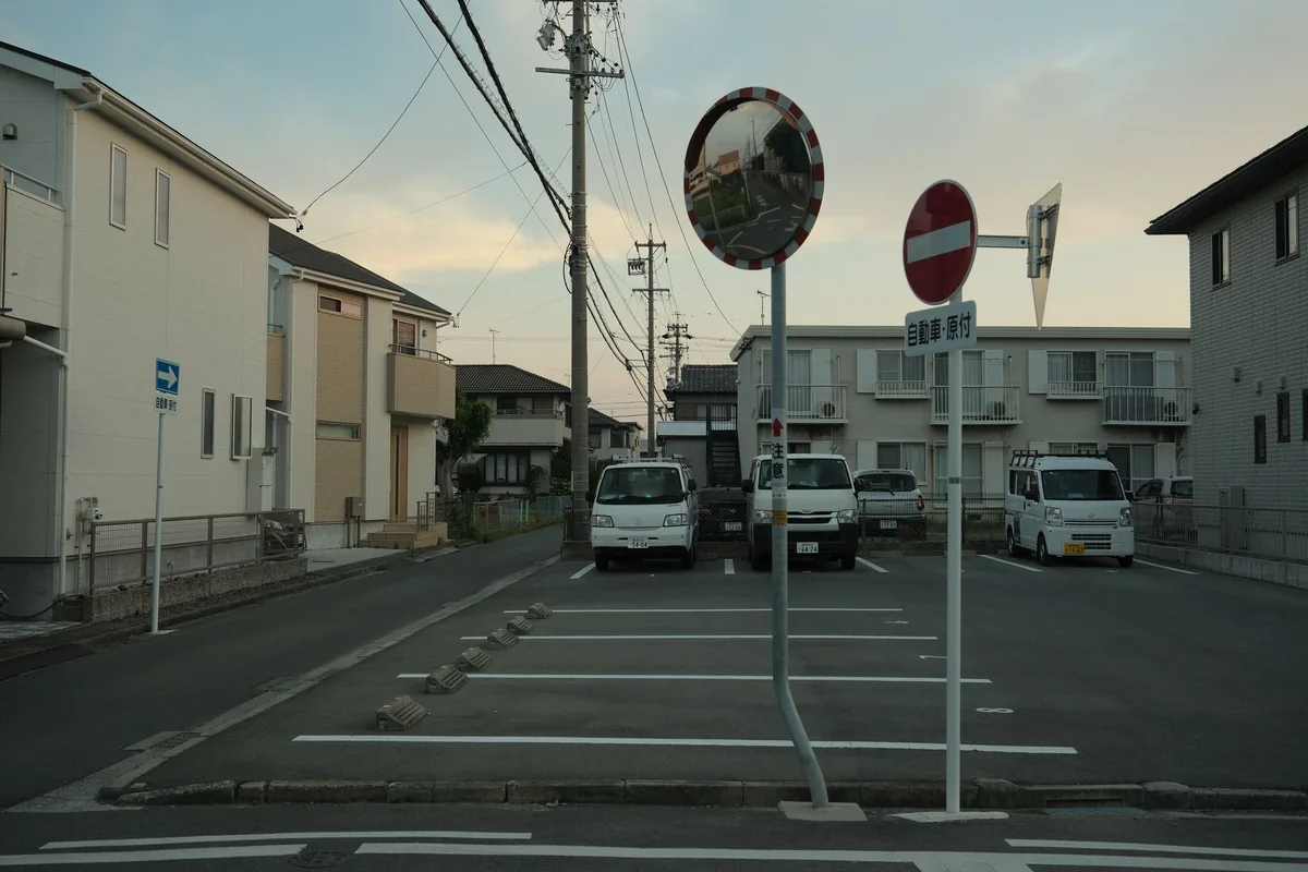 住宅が近接して建ち並ぶ住宅街の道路と、その脇の駐車スペース(イメージ写真)